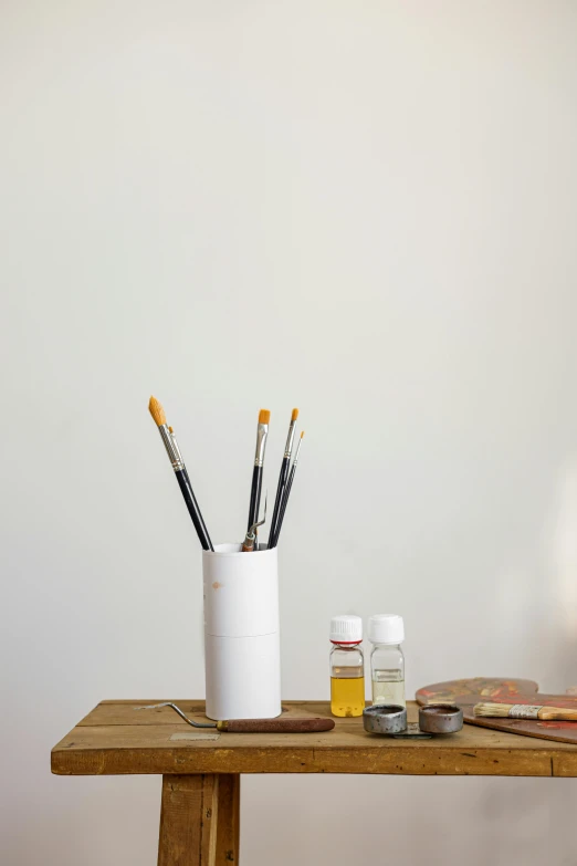 the table has a glass full of paintbrushes on it