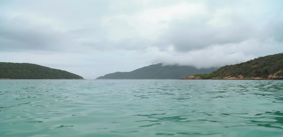 a group of hills sitting on the shore with water in front of them