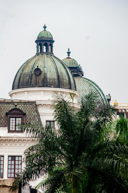 an old white building with green dome roofs