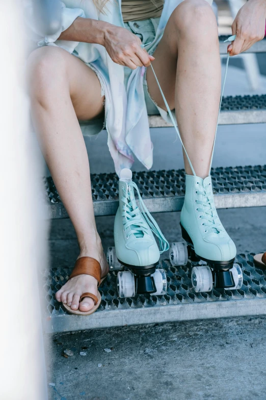 a woman wearing blue roller skates is sitting on the step