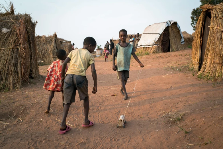 children playing soccer in the dirt outside a village