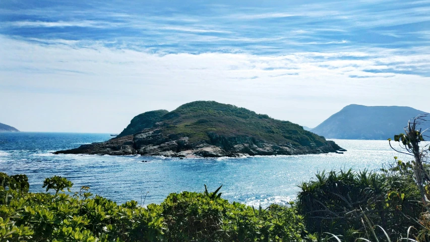 an island off the coast with two mountains in the background