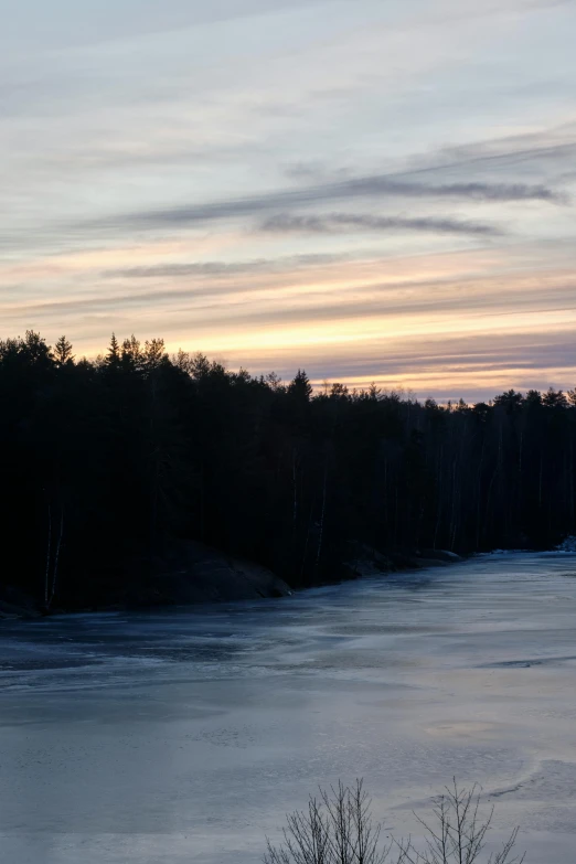 a boat floating on top of a frozen lake surrounded by woods