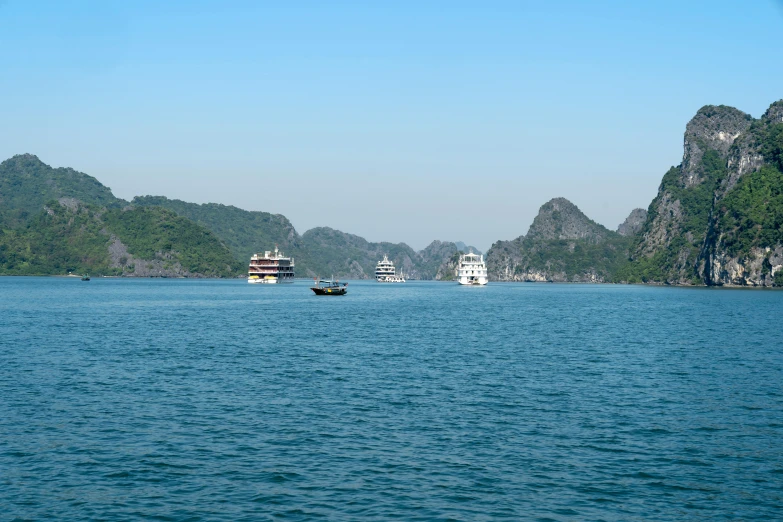 many boats are seen in the water near some mountains