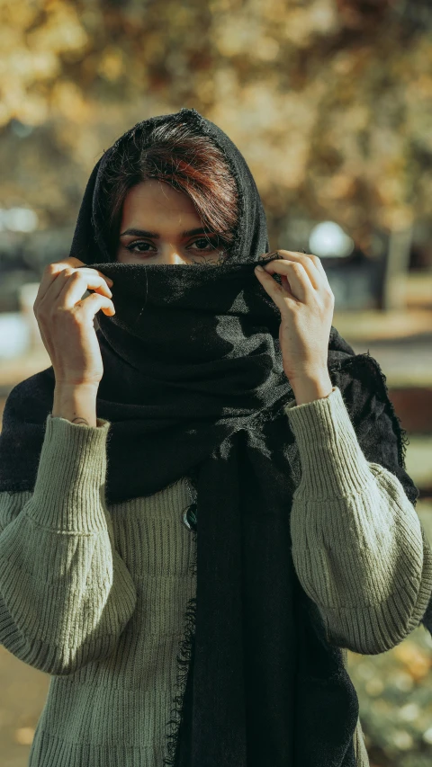 a woman standing in the park and covering her face