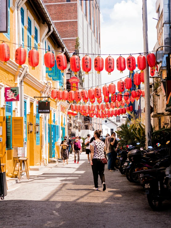 there are many people walking down the street and lanterns strung over