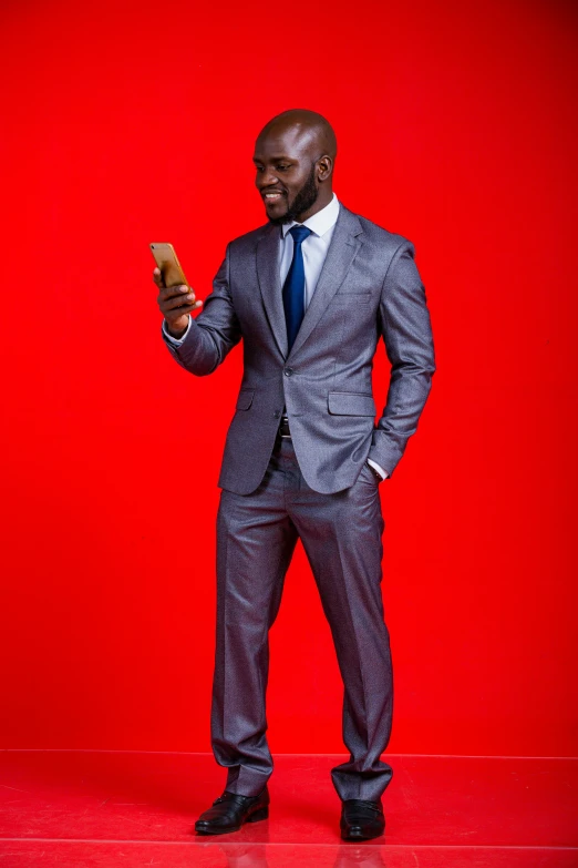 a man wearing a suit standing in a red background