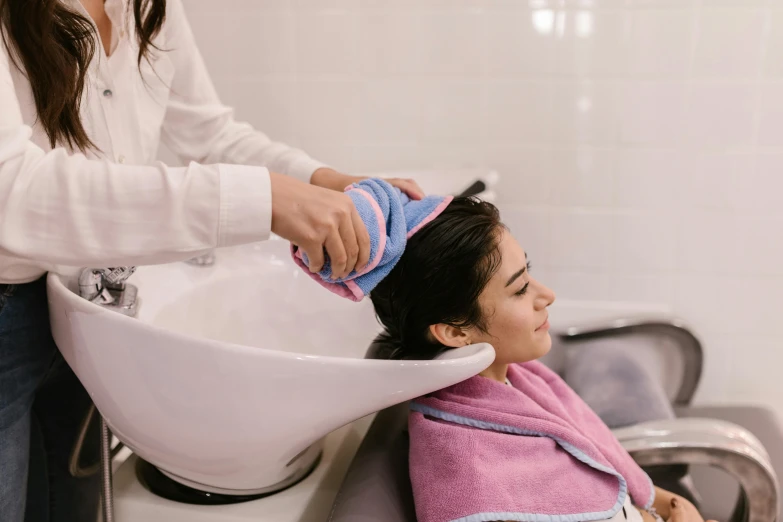 a woman is drying her hair at the salon