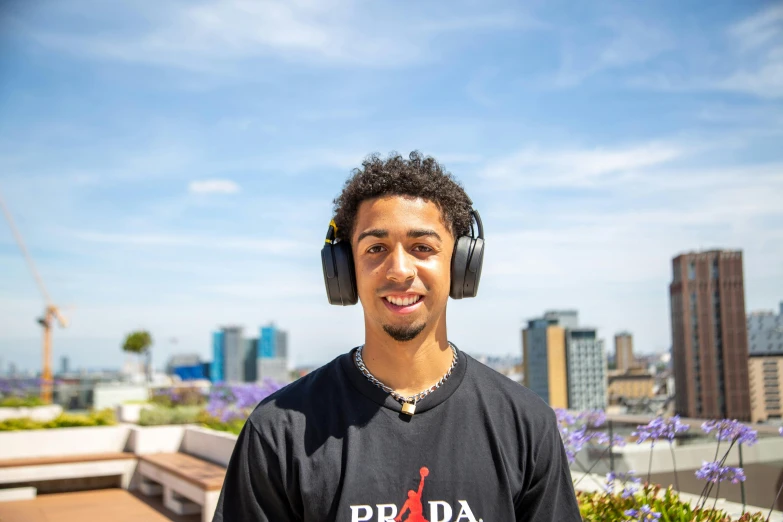 a smiling man wearing headphones on top of a building