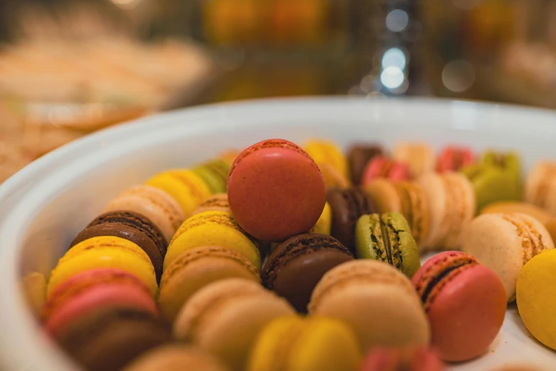 a white bowl filled with lots of colorful doughnuts