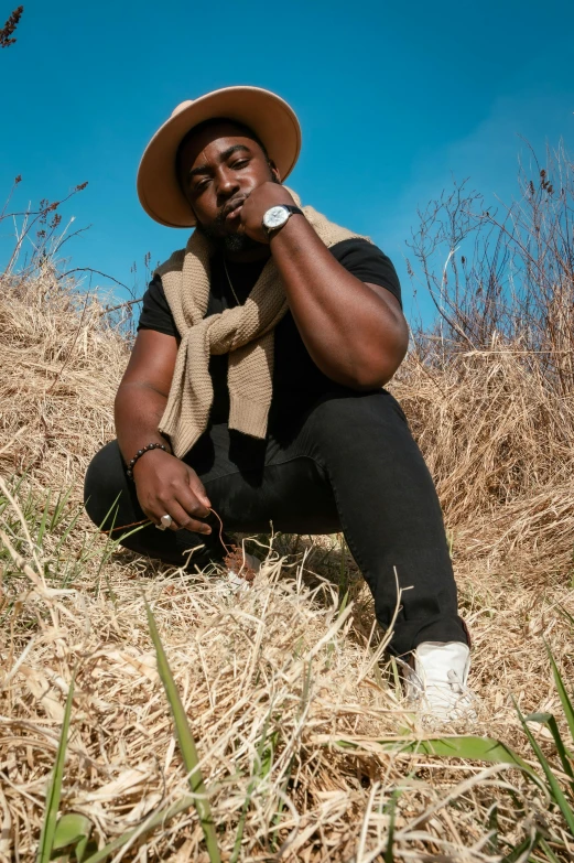 a man sitting on top of a dry grass covered hillside