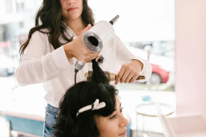 a woman in white shirt  another women hair