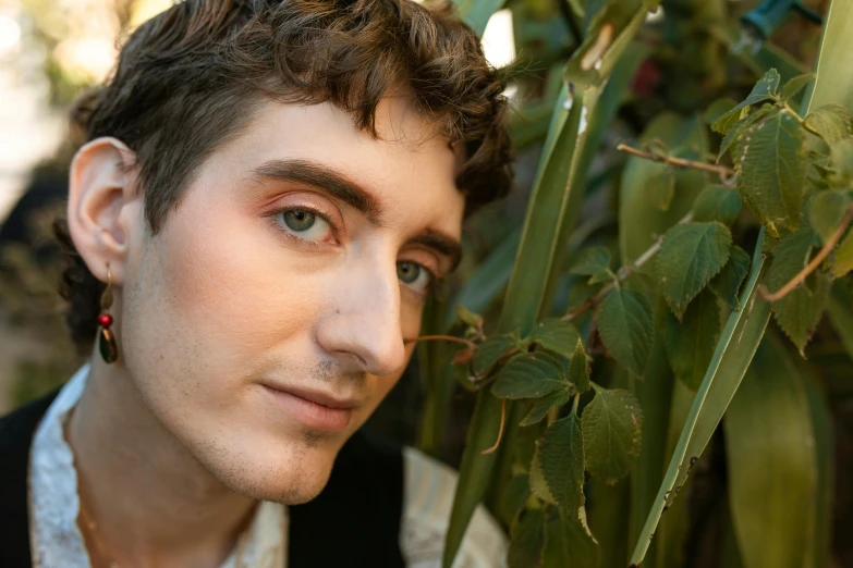 the young man is standing by the bush and flowers