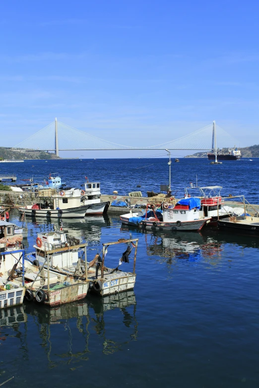 some ships are docked in the water under a bridge