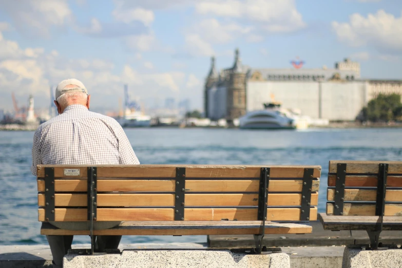 an older gentleman sitting on a bench near the water