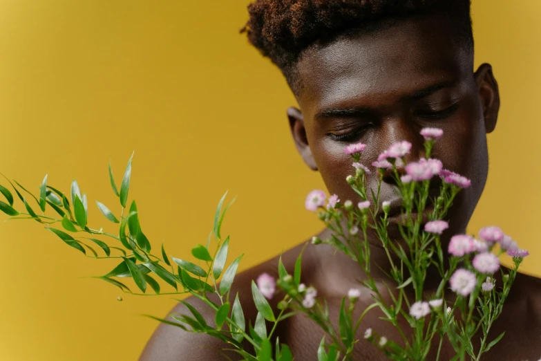 a young black man holding some flowers and looking at the camera