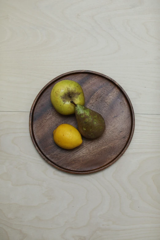 three pears and an apple in a wood bowl