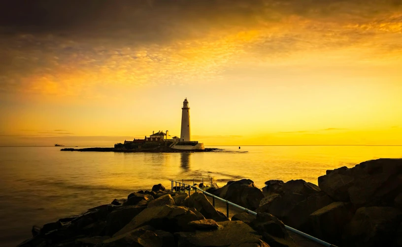 a lighthouse on the ocean during a sunset