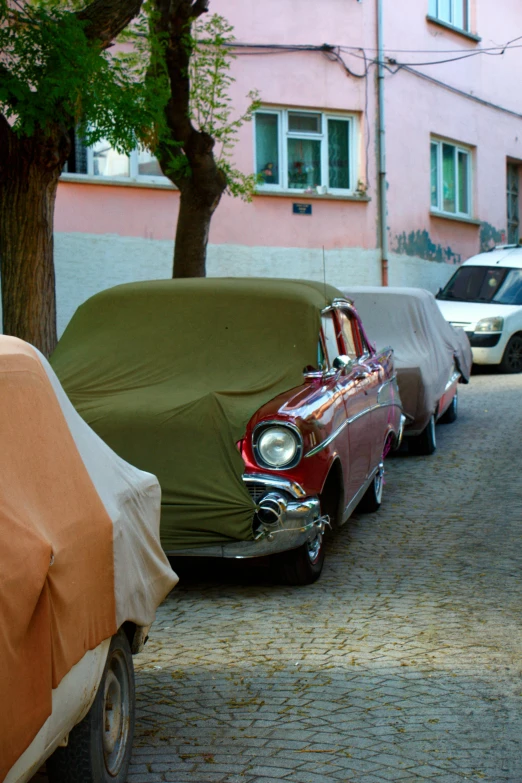 three cars parked side by side under covering on the street