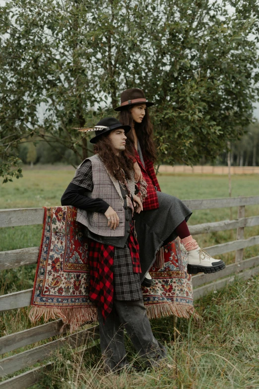 two women dressed in native american clothes sitting on a fence