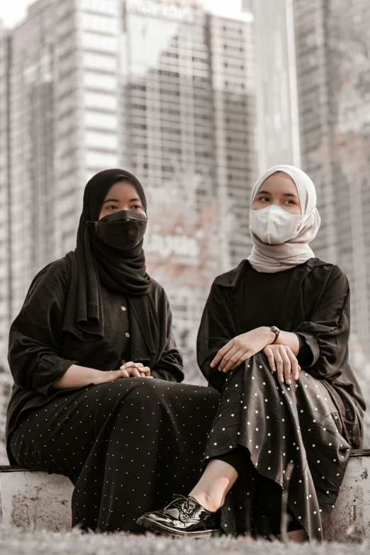 two women sitting on a wall with the skyline in the background