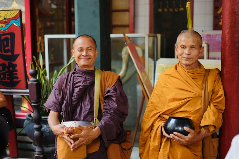 two buddhist monks in orange robes holding bowls of food