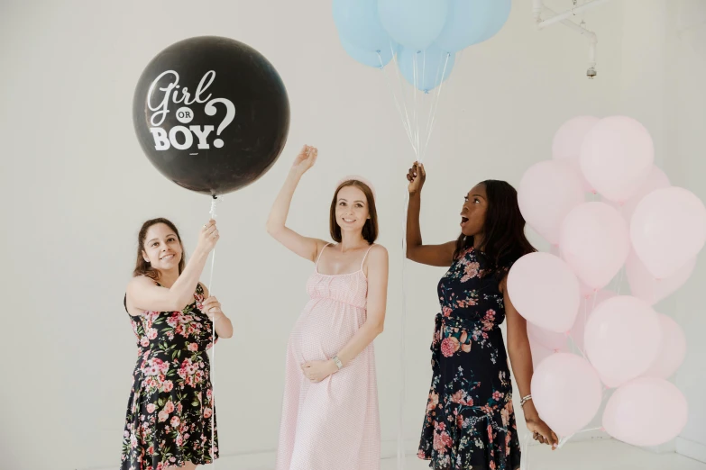 a couple of women standing holding balloons while standing next to each other