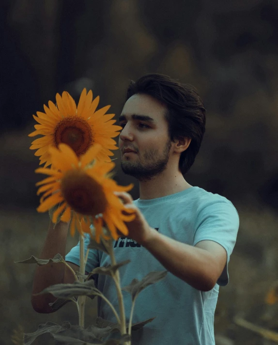 a man holding onto a sunflower in the woods