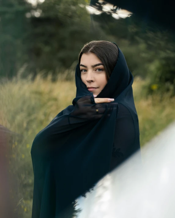 a woman in a black hooded jacket pointing at soing