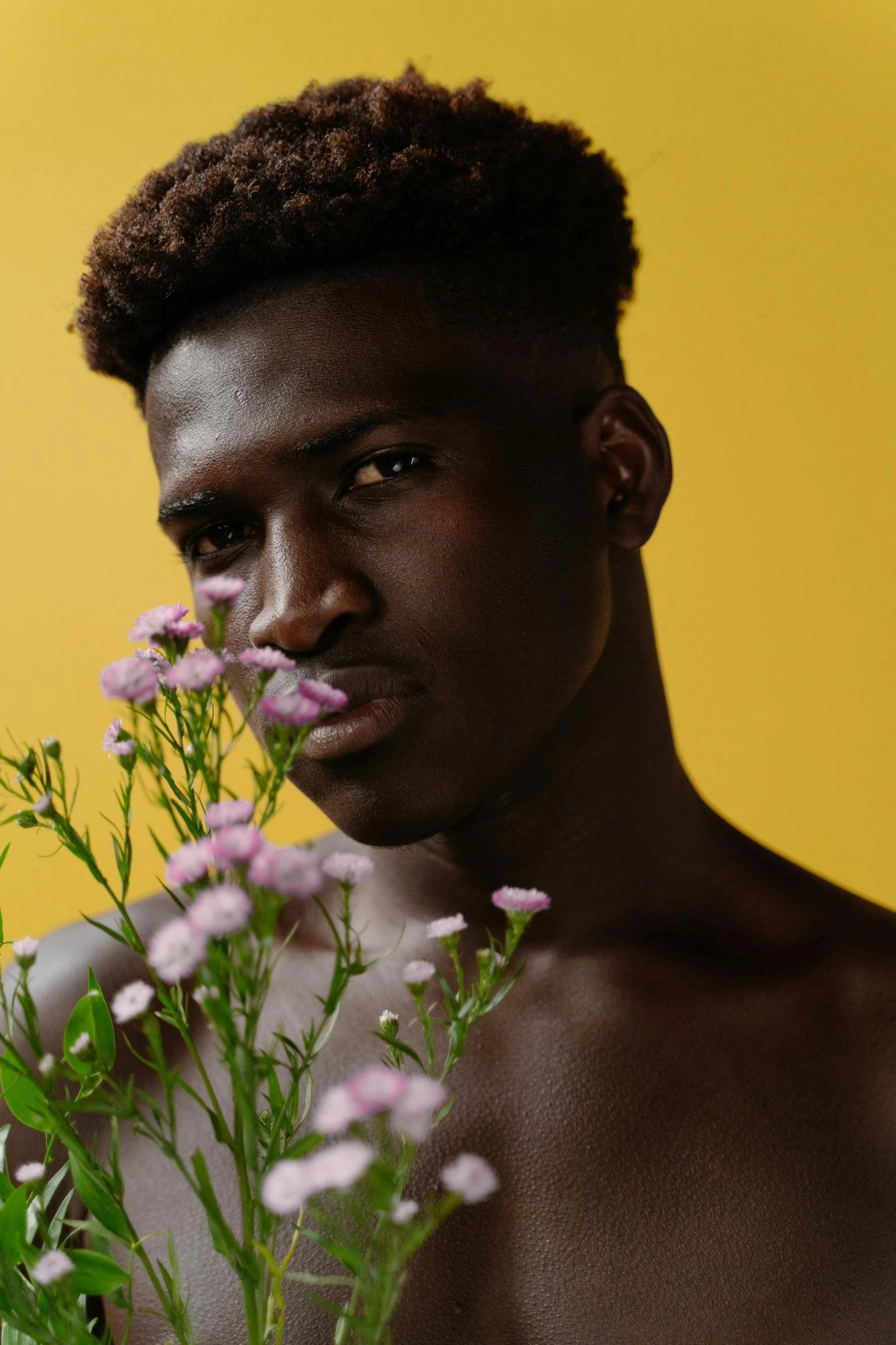 a young man poses for a portrait with flowers