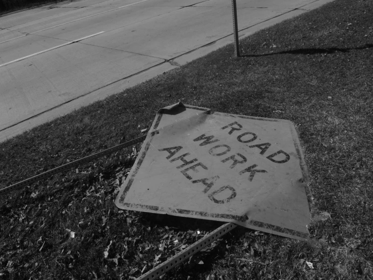 a sign that is in the grass on the side of the street