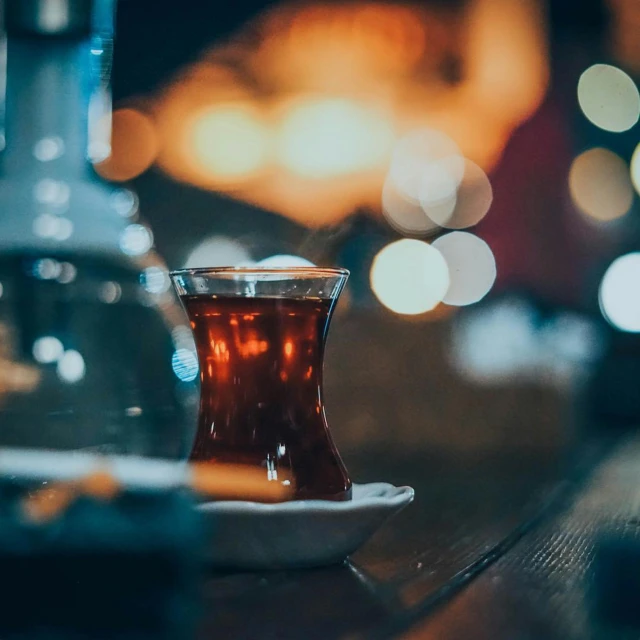 a glass filled with tea sitting on top of a table