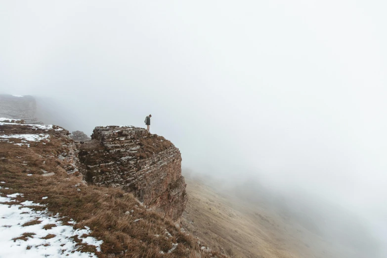 a person standing on a cliff in the middle of the snow