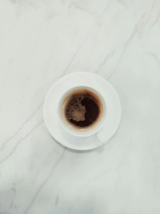 a cup of coffee sitting on top of a white marble counter top