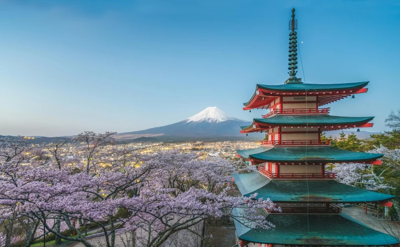 pagodas with colorful cherry blossoms in the foreground and a mountain in the background