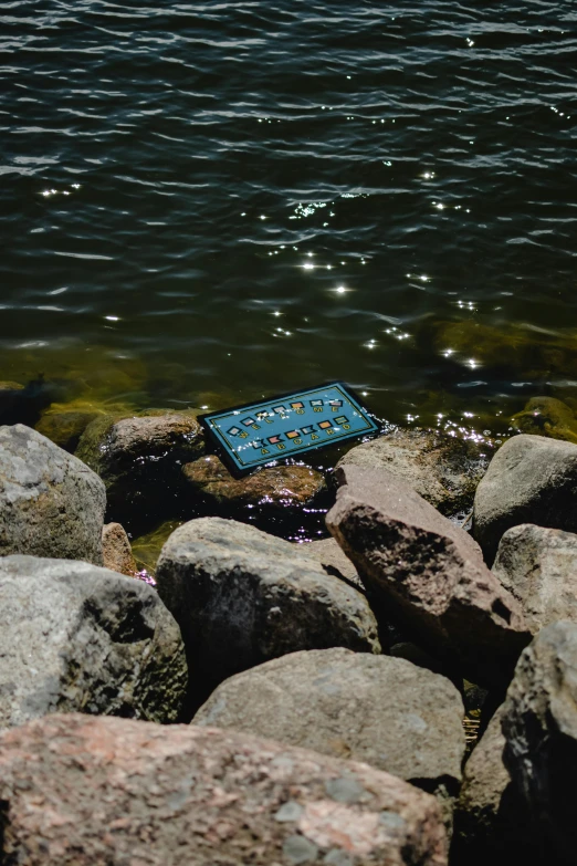 a blue mat with beads on it in the water surrounded by rocks