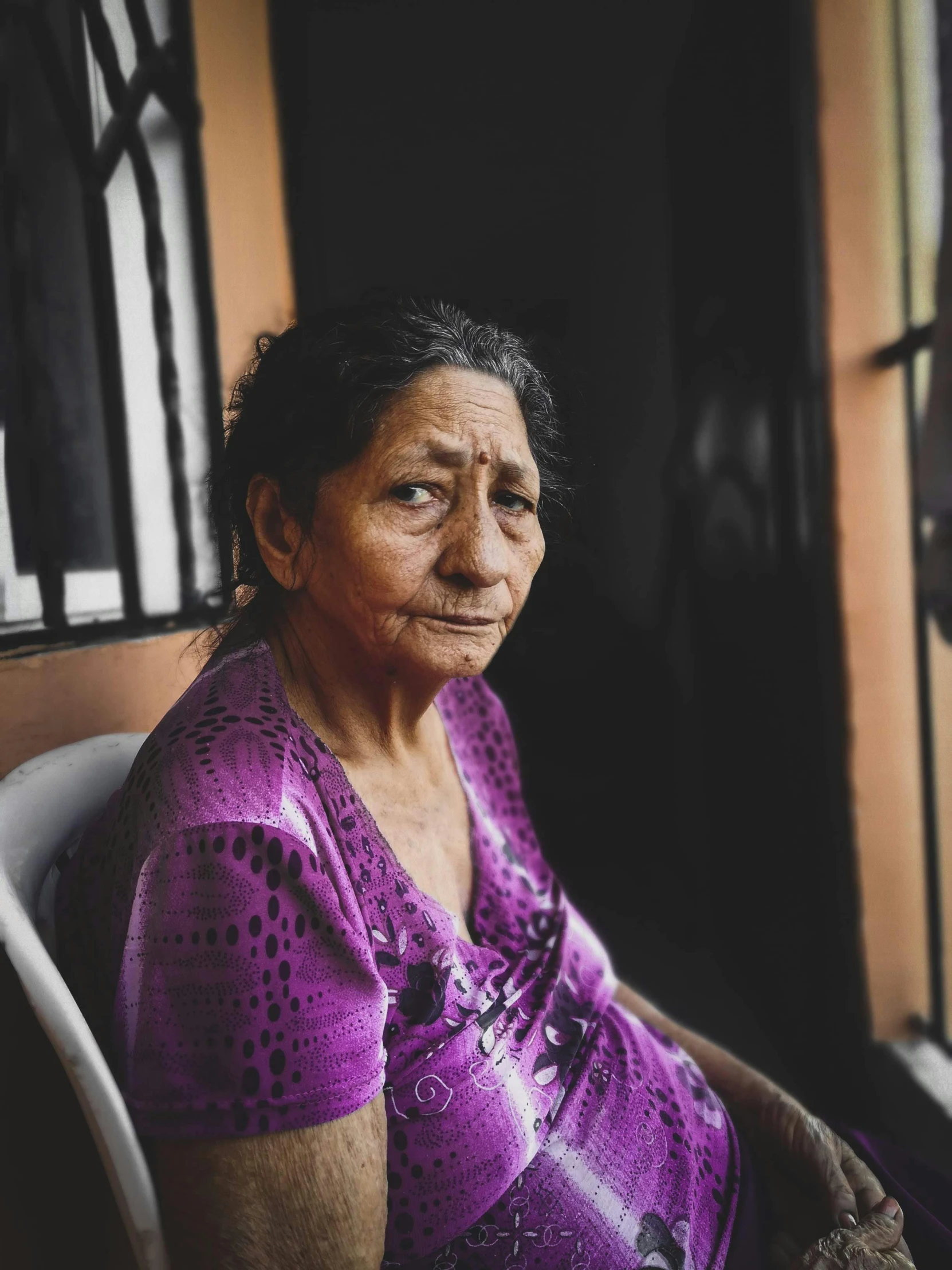 a woman looking out a window sitting in a chair