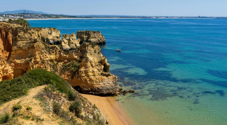 view of a beach in front of cliffs with clear water