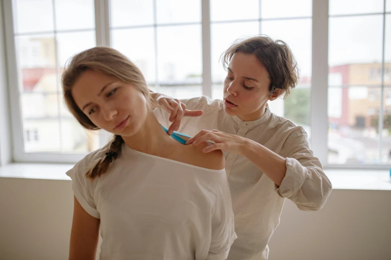 two women getting their hair trimmed while wearing white shirts