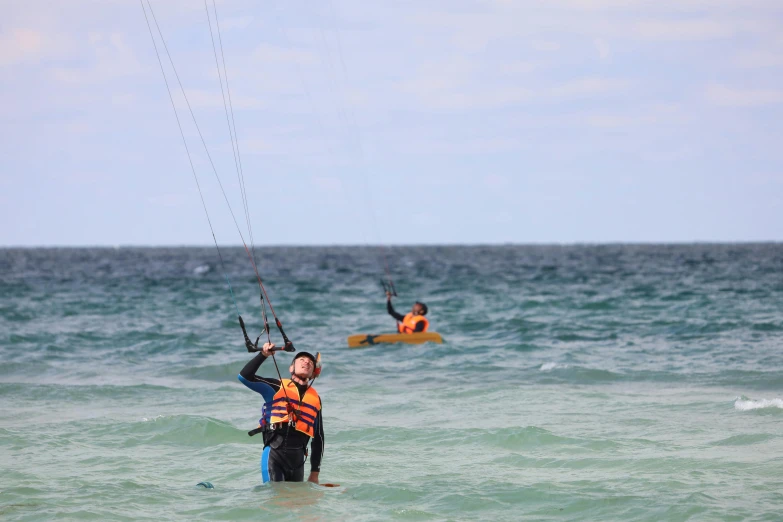 two people standing in the ocean with parasails