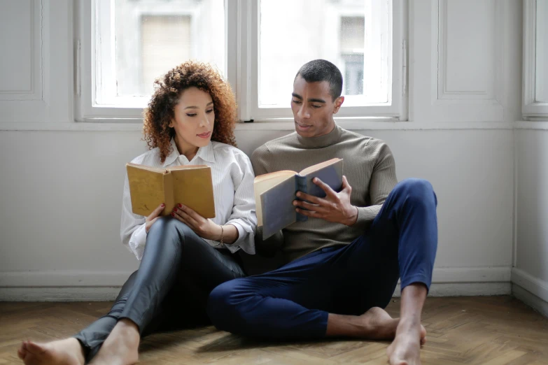 the man and woman are sitting together reading