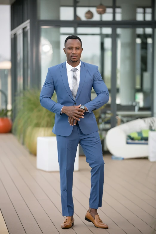 a man in blue suit posing on a boardwalk