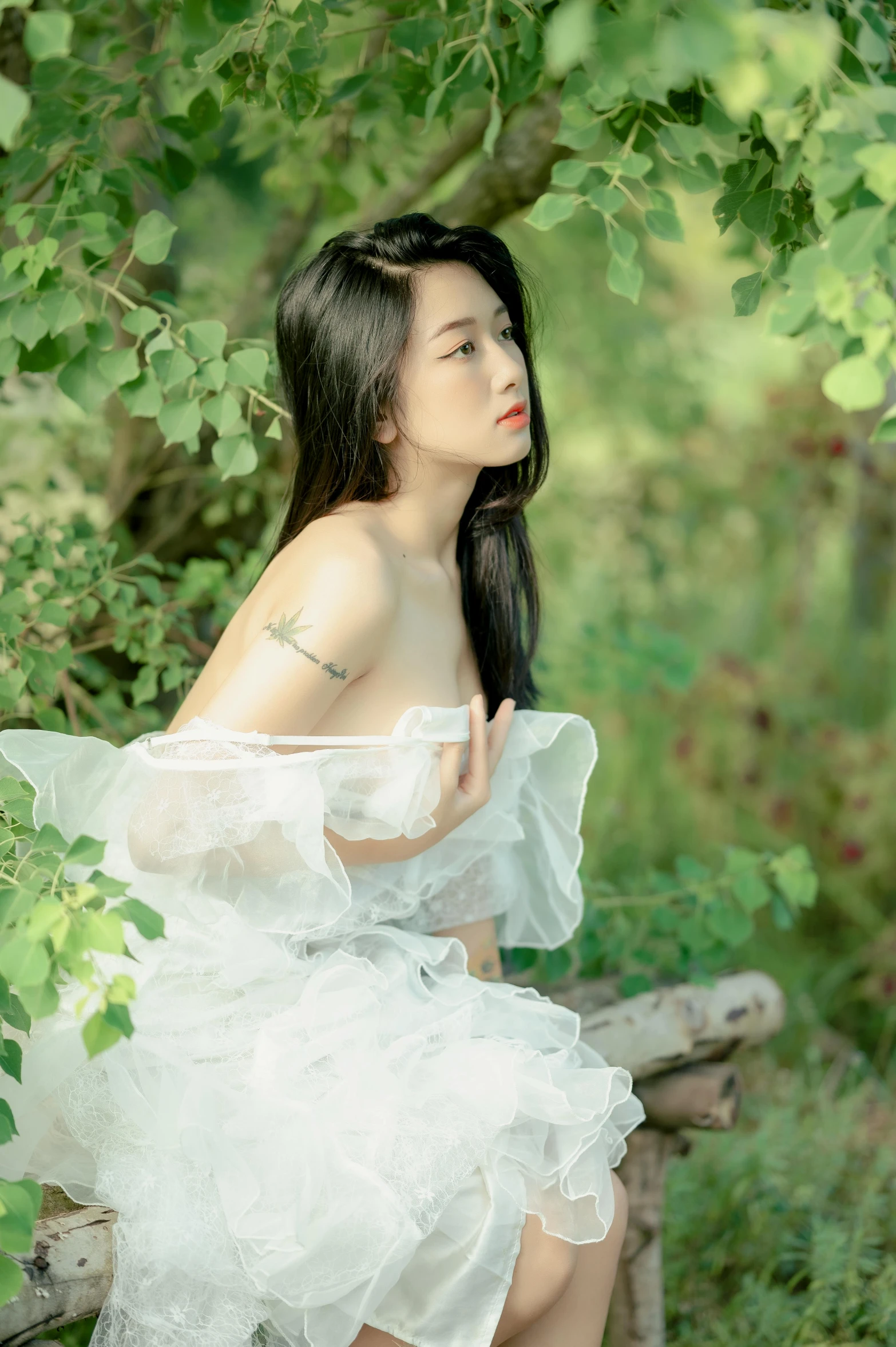 a woman sits under a tree wearing a short white dress