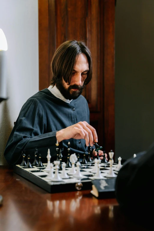 a man sitting down playing chess on a board