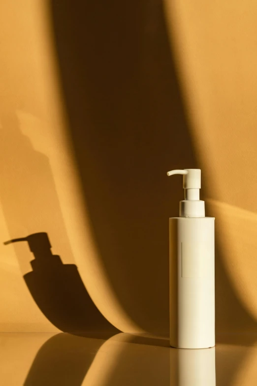 a soap dispenser is shown in shadow against the wall