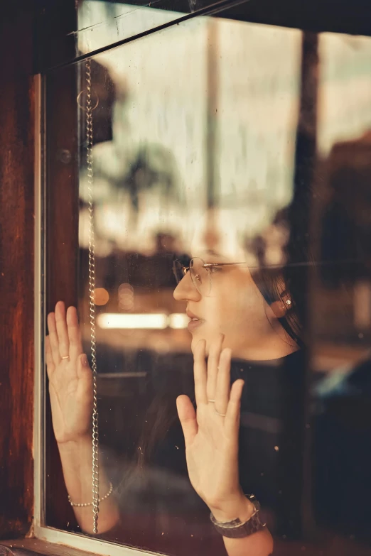 the woman is looking out the window while holding her hand up to her face