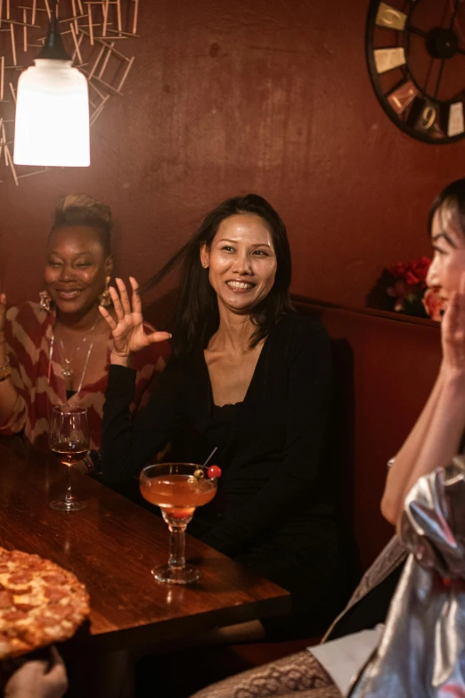 three women are gathered at the bar and have drinks