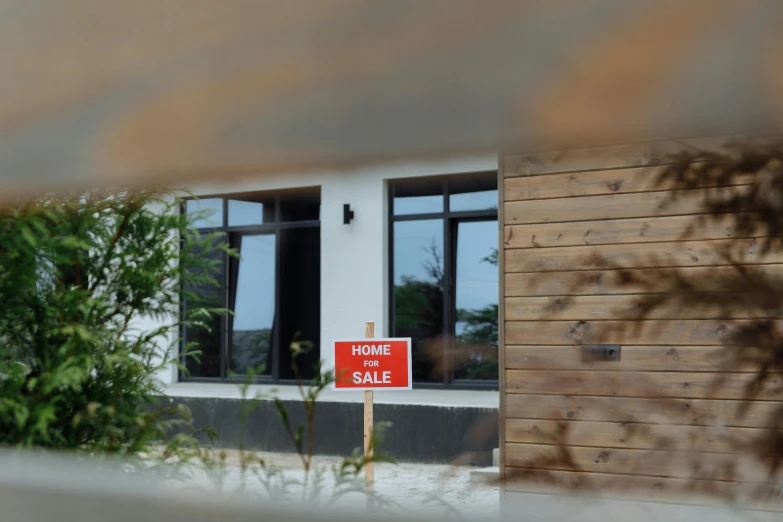 an orange home for sale sign sitting outside of a house