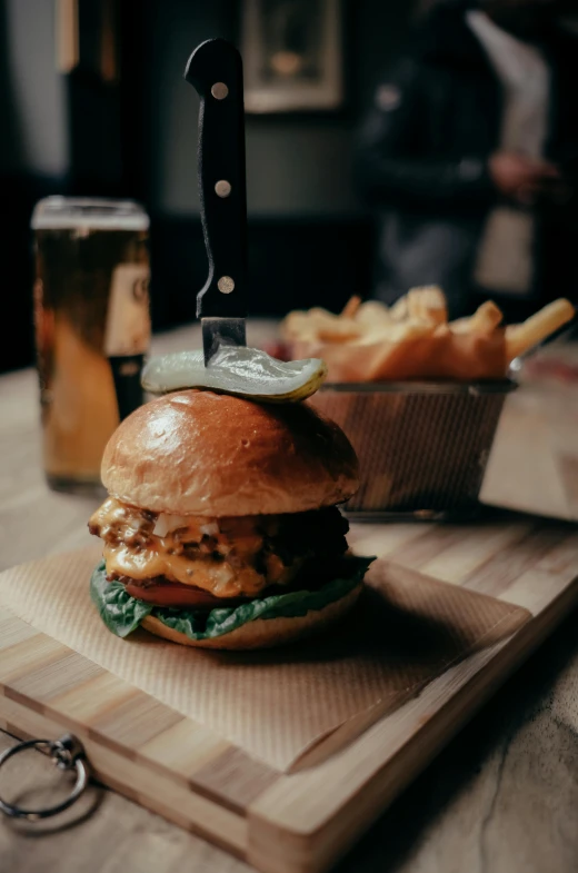 a sandwich sitting on top of a wooden  board with a knife next to it