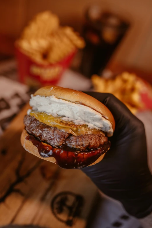 a man holding a hamburger with a lot of cheese and tomatoes